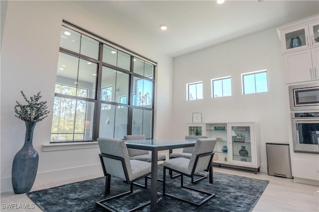 dining area with light wood-style flooring, recessed lighting, and a high ceiling
