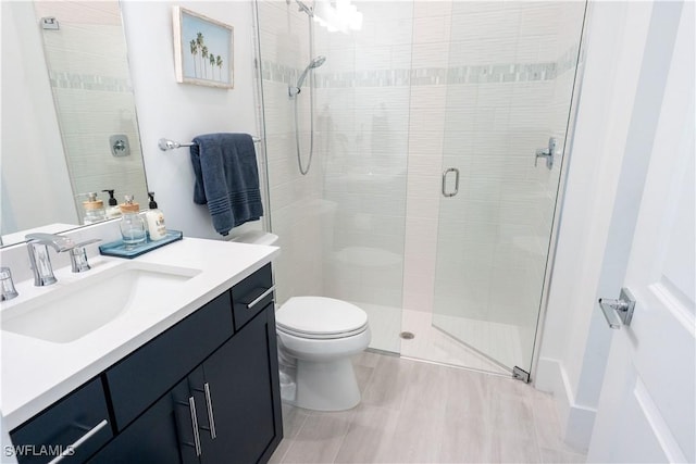 bathroom with a shower stall, vanity, toilet, and wood finished floors