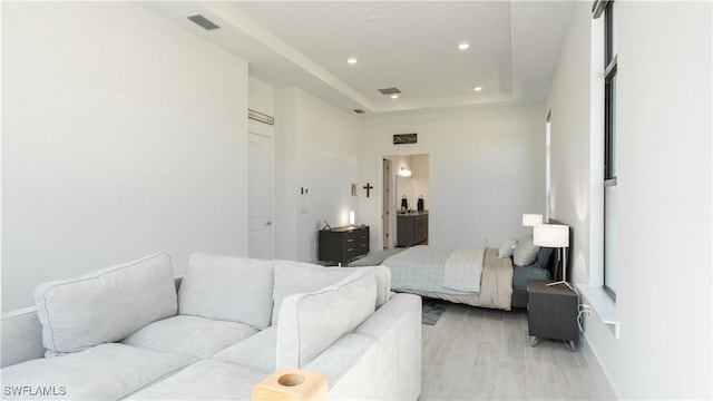 bedroom with a raised ceiling, ensuite bathroom, visible vents, and recessed lighting
