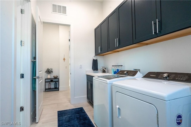 clothes washing area with light wood finished floors, cabinet space, visible vents, baseboards, and independent washer and dryer
