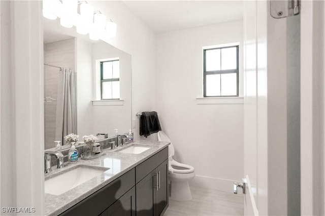 full bathroom with double vanity, toilet, baseboards, and a sink