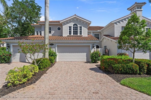 9083 Cascada Way Unit 101, Naples, FL 34114 - mediterranean / spanish-style house featuring a tile roof, stucco siding, decorative driveway, and a garage