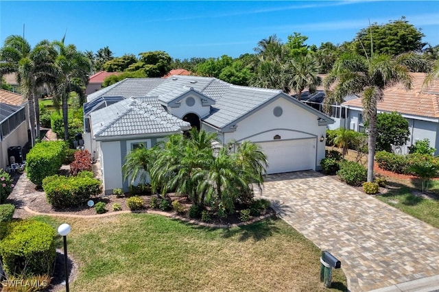 ranch-style house with driveway, a tiled roof, an attached garage, stucco siding, and a front yard