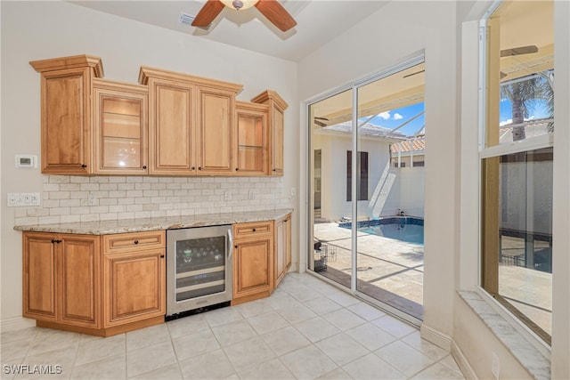 kitchen with decorative backsplash, light stone countertops, ceiling fan, and wine cooler