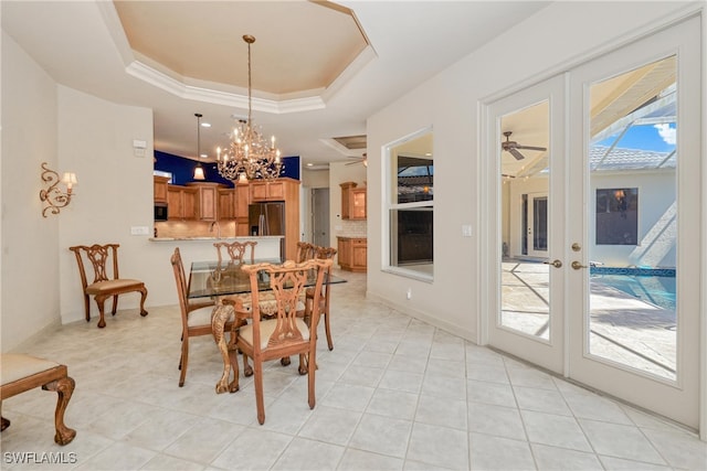 dining space featuring plenty of natural light, french doors, a raised ceiling, and ceiling fan with notable chandelier