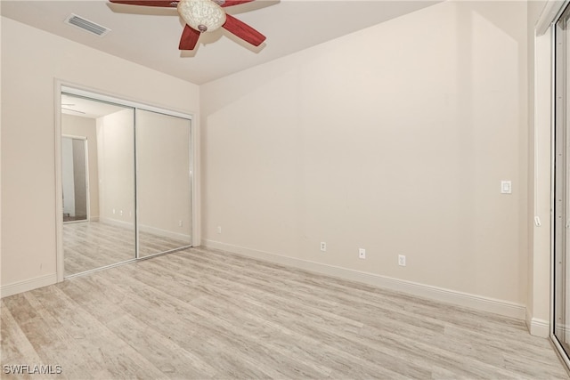 unfurnished bedroom with a closet, light wood-type flooring, visible vents, ceiling fan, and baseboards