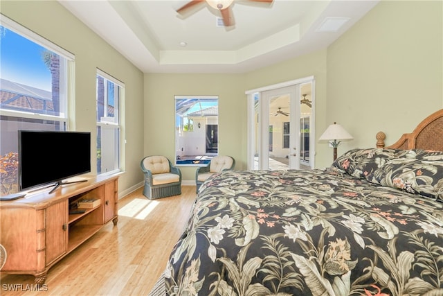 bedroom featuring ceiling fan, a tray ceiling, and light wood-type flooring