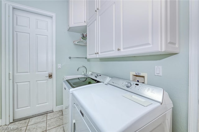 laundry room with light tile patterned floors, a sink, cabinet space, washing machine and clothes dryer, and baseboards
