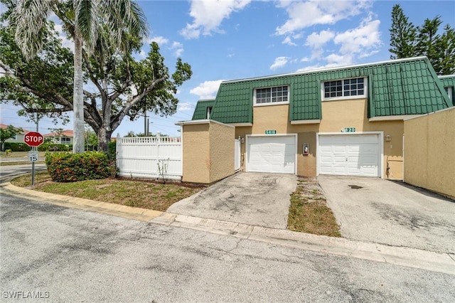 5816 Whiting Ct, Fort Myers, FL 33919 - view of property with stucco siding, asphalt driveway, fence, mansard roof, and a garage