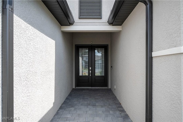 view of exterior entry featuring stucco siding and french doors