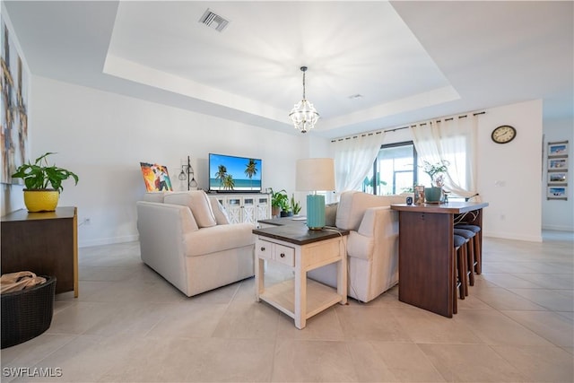 living room with a chandelier, visible vents, baseboards, and a raised ceiling