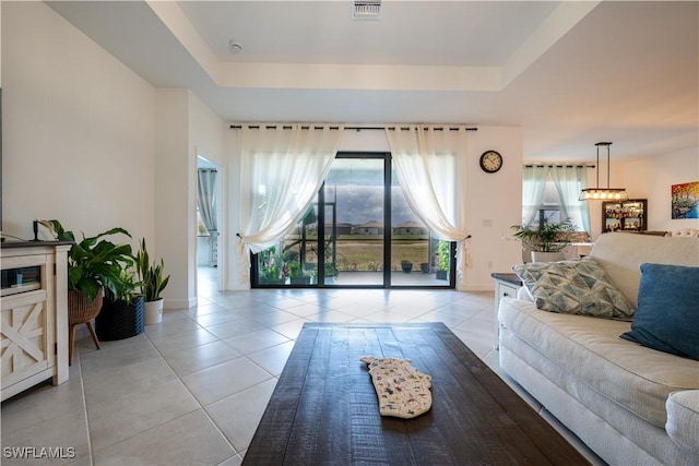 living room with a tray ceiling, light tile patterned floors, plenty of natural light, and baseboards
