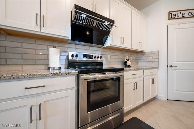 kitchen featuring light stone countertops, light tile patterned flooring, backsplash, stainless steel range with electric stovetop, and white cabinets