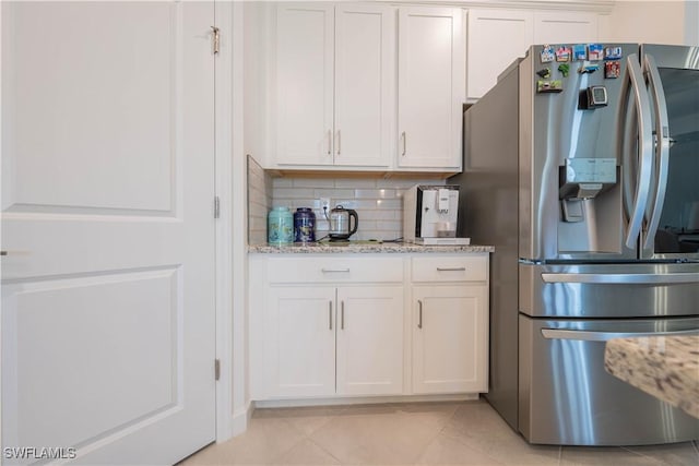 kitchen featuring light stone counters, white cabinetry, backsplash, light tile patterned floors, and stainless steel fridge with ice dispenser
