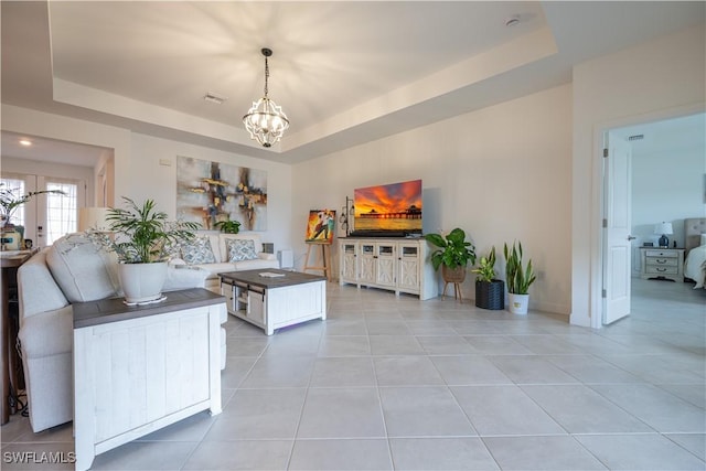 living room featuring an inviting chandelier, light tile patterned floors, and a raised ceiling