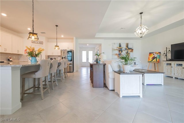 kitchen with light tile patterned flooring, a spacious island, recessed lighting, white cabinetry, and decorative backsplash