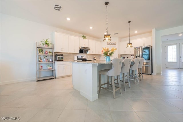 kitchen featuring light tile patterned floors, a breakfast bar, white cabinetry, backsplash, and appliances with stainless steel finishes