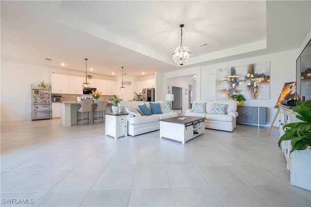 living area with light tile patterned flooring, recessed lighting, a chandelier, a raised ceiling, and baseboards