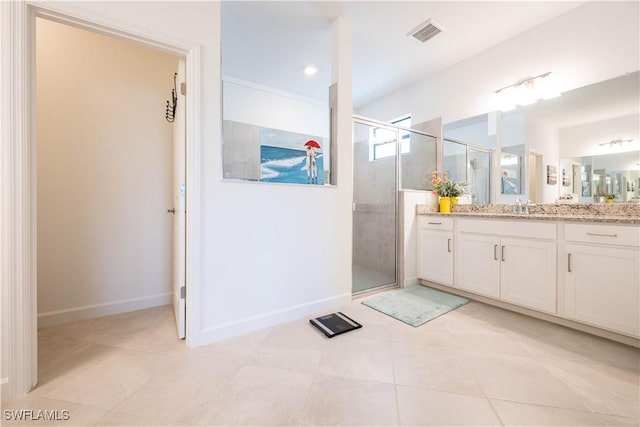 full bath featuring a stall shower, tile patterned flooring, vanity, and baseboards