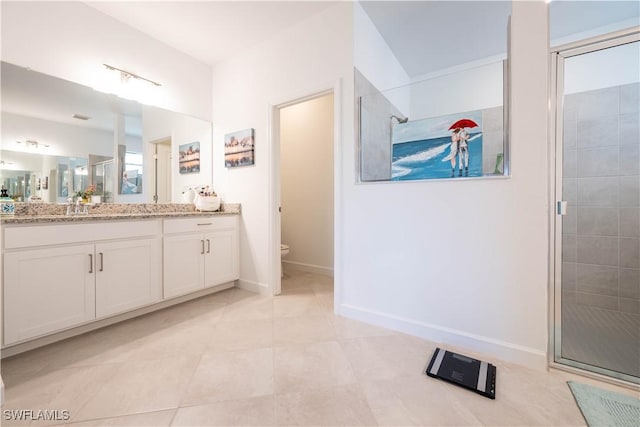 bathroom featuring a shower stall, toilet, vanity, tile patterned flooring, and baseboards