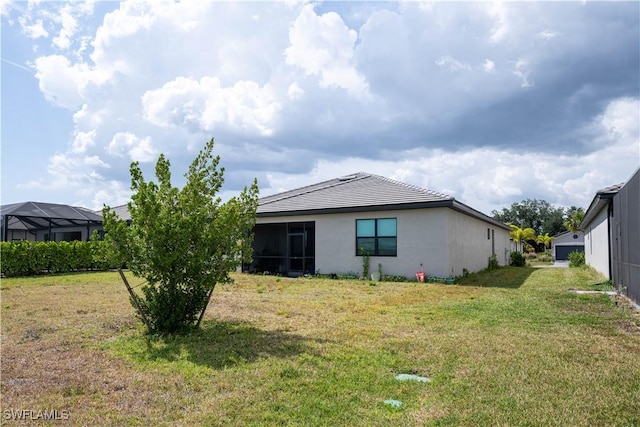 back of house with a lawn and stucco siding
