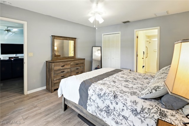 bedroom with a closet, wood finished floors, ensuite bath, visible vents, and baseboards