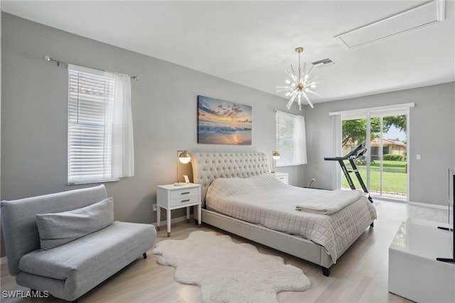 bedroom featuring access to outside, light wood-type flooring, and attic access