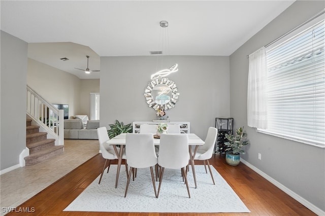 dining space featuring wood finished floors, baseboards, stairs, and a ceiling fan