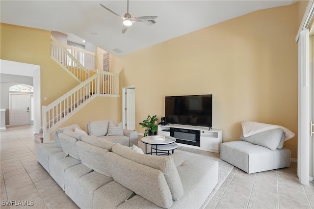 living room featuring high vaulted ceiling, light tile patterned flooring, stairway, ceiling fan, and baseboards
