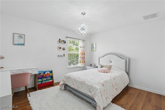 bedroom featuring a chandelier, wood finished floors, and baseboards