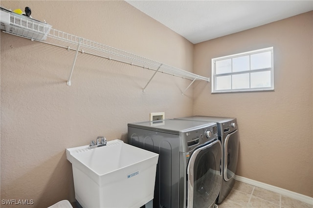 laundry area with washer and clothes dryer, baseboards, and light tile patterned flooring