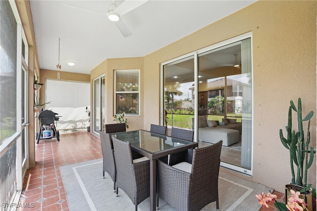 sunroom / solarium with a ceiling fan, tile patterned floors, and outdoor dining space