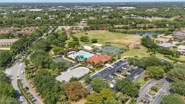 aerial view of property and surrounding area featuring a nearby body of water, a pool area, and a golf course