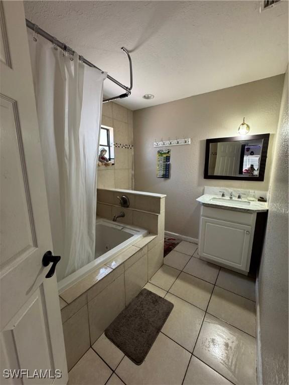 27831 Quinn St, Bonita Springs, FL 34135 - full bath featuring tiled shower / bath combo, a textured ceiling, baseboards, tile patterned flooring, and vanity