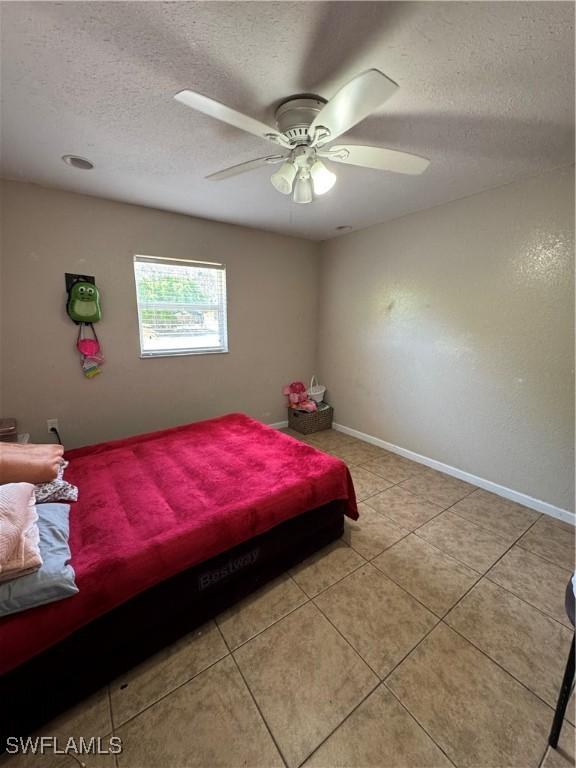 27831 Quinn St, Bonita Springs, FL 34135 - bedroom with a textured ceiling, light tile patterned flooring, a ceiling fan, and baseboards