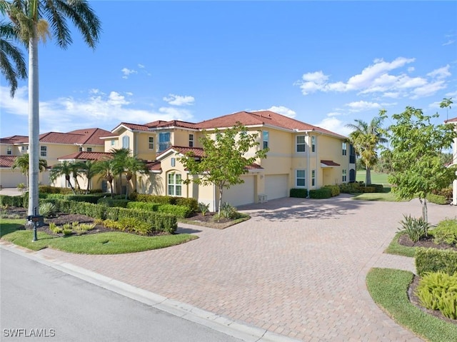 mediterranean / spanish-style home featuring driveway, stucco siding, a residential view, and a garage