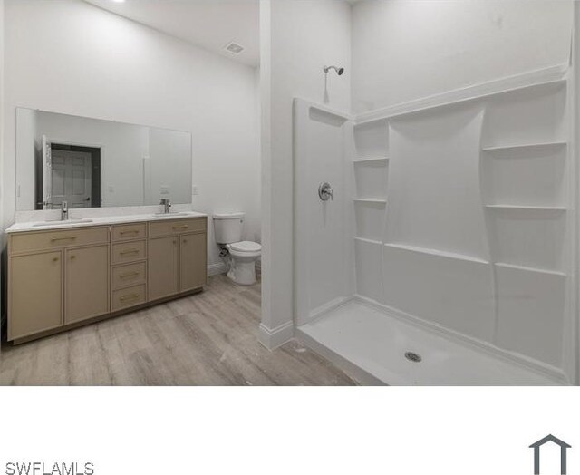 706 Glacier Ave, Lehigh Acres, FL 33974 - bathroom featuring toilet, a shower, wood finished floors, double vanity, and baseboards