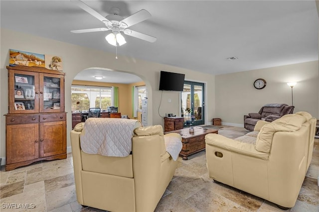 1331 Rio Vista Ave, Fort Myers, FL 33901 - living room with arched walkways, stone tile flooring, ceiling fan, and baseboards