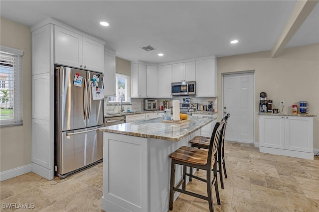 1331 Rio Vista Ave, Fort Myers, FL 33901 - kitchen with stainless steel appliances, stone tile floors, white cabinetry, baseboards, and light stone counters
