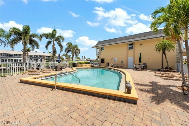 community pool with a patio area and fence