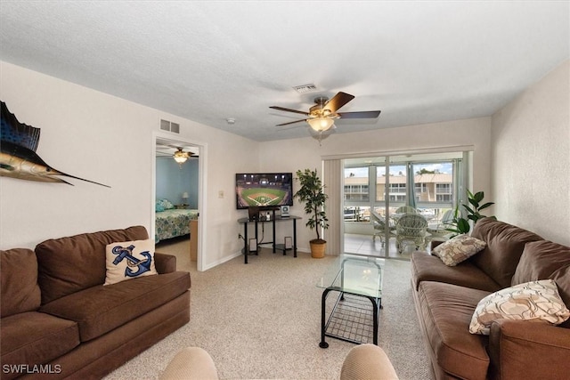 living area featuring baseboards, ceiling fan, visible vents, and light colored carpet