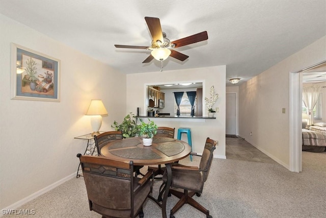 carpeted dining room with baseboards and a ceiling fan