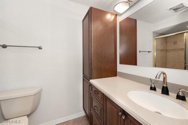 bathroom featuring toilet, vanity, visible vents, baseboards, and a tile shower