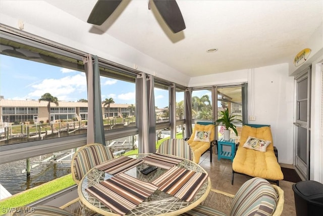 sunroom featuring a water view and a ceiling fan