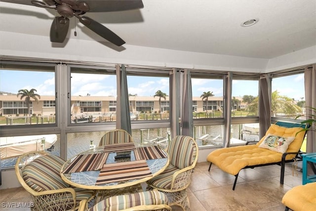 sunroom / solarium with a water view, tile patterned flooring, and a residential view