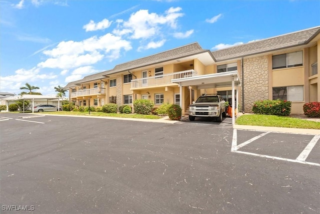 view of property featuring covered and uncovered parking