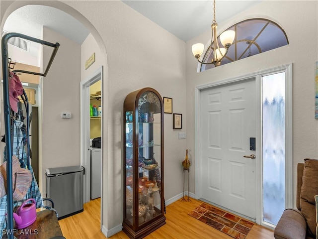 507 NE 31st St, Cape Coral, FL 33909 - foyer featuring an inviting chandelier, arched walkways, washer / dryer, and light wood-style floors