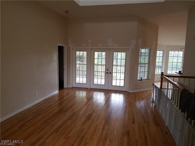 880 18th St NE, Naples, FL 34120 - unfurnished living room featuring baseboards, french doors, a high ceiling, and wood finished floors
