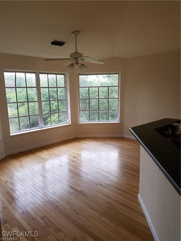880 18th St NE, Naples, FL 34120 - unfurnished living room with a wealth of natural light, baseboards, and ceiling fan