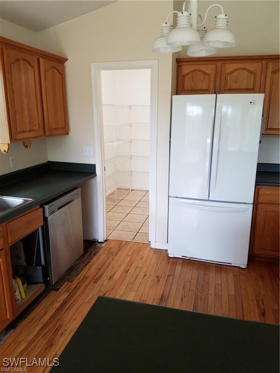 880 18th St NE, Naples, FL 34120 - kitchen with freestanding refrigerator, dishwasher, light wood-type flooring, and dark countertops